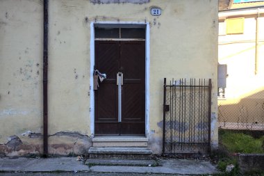 Kırsal bir yolun gölgesinde aşınmış bir dış kapı ve cephe