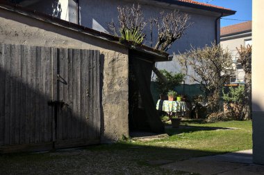 Bir kır evinin arka bahçesi ve yakından görülen bir kulübe.