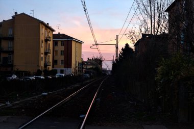 Demiryolu kışın gün batımında gölgede geçiyor.