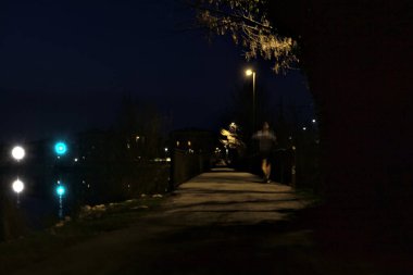 Gece bir gölün üzerindeki köprüde sokak lambalarıyla dolu bir geçit.