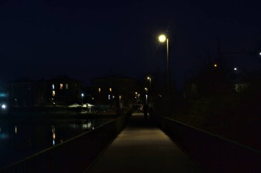 Gece bir gölün üzerindeki köprüde sokak lambalarıyla dolu bir geçit.