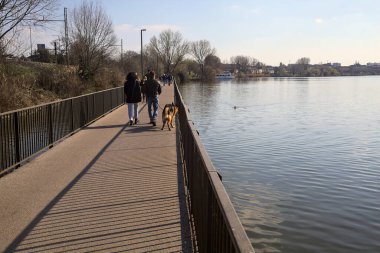 Güneşli bir günde insanların yürüdüğü bir göldeki köprü.