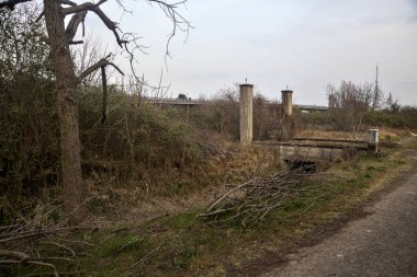 Karanlık çöktüğünde, bulutlu bir günde, bir kapısı ve çıplak ağaçları olan bir köy yolu.