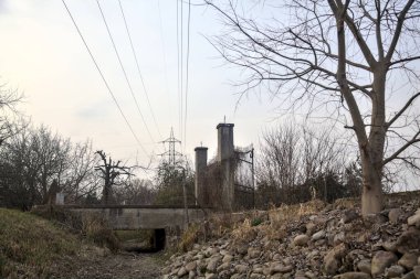 Karanlık çöktüğünde, bulutlu bir günde, bir kapısı ve çıplak ağaçları olan bir köy yolu.