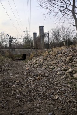 Karanlık çöktüğünde, bulutlu bir günde, bir kapısı ve çıplak ağaçları olan bir köy yolu.