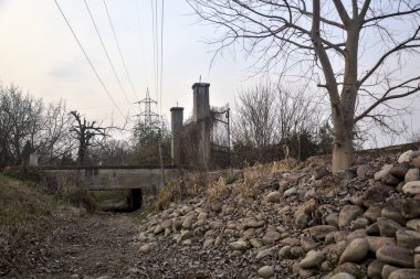 Karanlık çöktüğünde, bulutlu bir günde, bir kapısı ve çıplak ağaçları olan bir köy yolu.