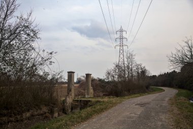 Bulutlu bir günde alacakaranlıkta, köy yolunun kenarındaki bir tarlaya giriş kapısı.