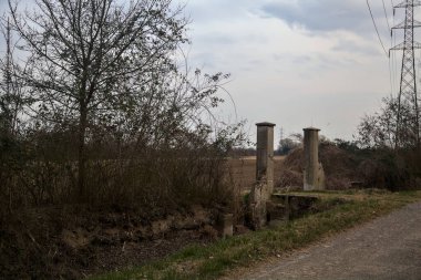 Bulutlu bir günde alacakaranlıkta, köy yolunun kenarındaki bir tarlaya giriş kapısı.