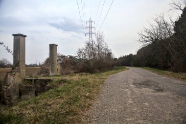 Bulutlu bir günde alacakaranlıkta, köy yolunun kenarındaki bir tarlaya giriş kapısı.