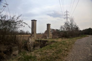 Bulutlu bir günde alacakaranlıkta, köy yolunun kenarındaki bir tarlaya giriş kapısı.