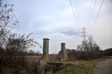 Bulutlu bir günde alacakaranlıkta, köy yolunun kenarındaki bir tarlaya giriş kapısı.