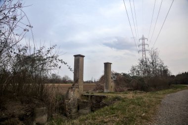 Bulutlu bir günde alacakaranlıkta, köy yolunun kenarındaki bir tarlaya giriş kapısı.