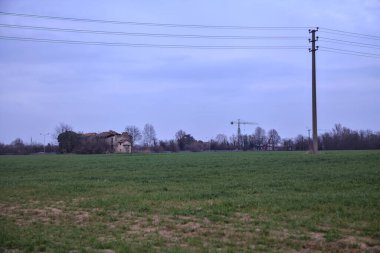 Terk edilmiş bir kır evinde, uzak bir tarlada, bulutlu bir günde, alacakaranlıkta.