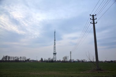 Bulutlu bir günde ekilmiş tarla. Uzakta bir radyo kulesi var.