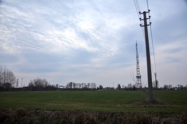 Bulutlu bir günde ekilmiş tarla. Uzakta bir radyo kulesi var.