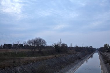 Alacakaranlıkta bulutlu bir günde, gökyüzünün suya döküldüğü bir hava kanalı.