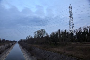 Alacakaranlıkta bulutlu bir günde, gökyüzünün suya döküldüğü bir hava kanalı.