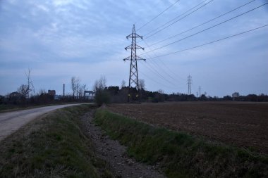 Bulutlu bir günde, alacakaranlıkta tarlaların yanındaki köy yolu.