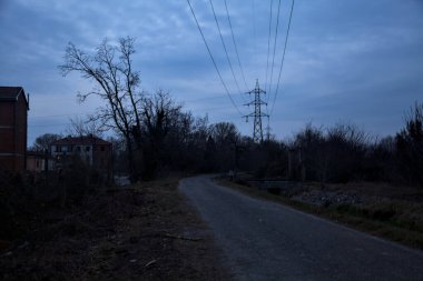 Bulutlu bir günde alacakaranlıkta, sınırında bir kapı olan kırsal bölgede yol