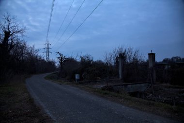 Bulutlu bir günde alacakaranlıkta, sınırında bir kapı olan kırsal bölgede yol