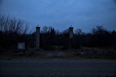 Bulutlu bir günde alacakaranlıkta, sınırında bir kapı olan kırsal bölgede yol