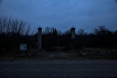 Bulutlu bir günde alacakaranlıkta, sınırında bir kapı olan kırsal bölgede yol