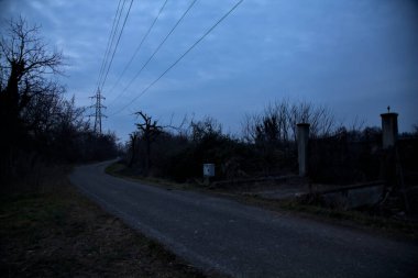 Bulutlu bir günde alacakaranlıkta, sınırında bir kapı olan kırsal bölgede yol