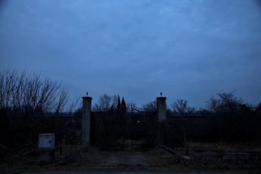 Bulutlu bir günde alacakaranlıkta, sınırında bir kapı olan kırsal bölgede yol