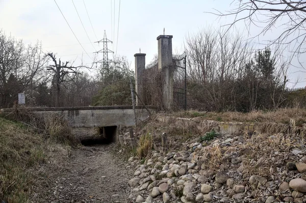 Karanlık çöktüğünde, bulutlu bir günde, bir kapısı ve çıplak ağaçları olan bir köy yolu.