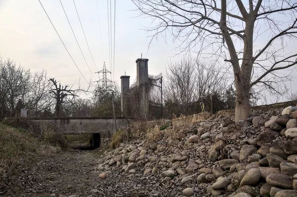 Karanlık çöktüğünde, bulutlu bir günde, bir kapısı ve çıplak ağaçları olan bir köy yolu.