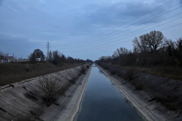 Alacakaranlıkta bulutlu bir günde, gökyüzünün suya döküldüğü bir hava kanalı.