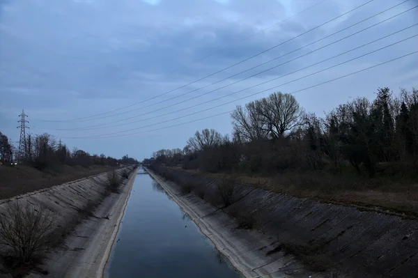 Alacakaranlıkta bulutlu bir günde, gökyüzünün suya döküldüğü bir hava kanalı.