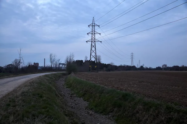 Bulutlu bir günde, alacakaranlıkta tarlaların yanındaki köy yolu.