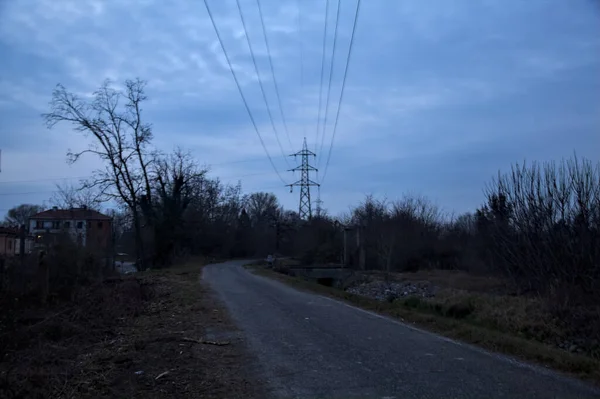 Bulutlu bir günde alacakaranlıkta, sınırında bir kapı olan kırsal bölgede yol