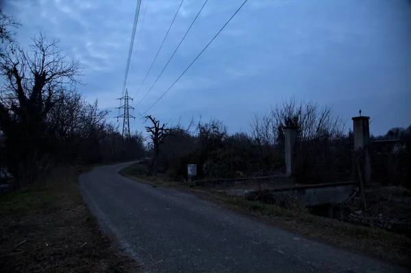 Bulutlu bir günde alacakaranlıkta, sınırında bir kapı olan kırsal bölgede yol