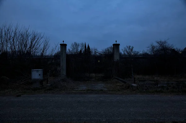 Bulutlu bir günde alacakaranlıkta, sınırında bir kapı olan kırsal bölgede yol