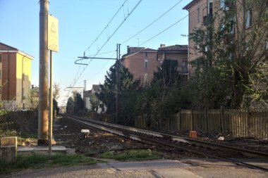 Gün batımında bir yerleşim alanının binalarının arasından geçen demiryolu hattı.