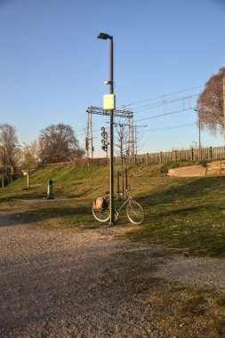 Gün batımında bir yola dayanan bisikletli sokak lambası.