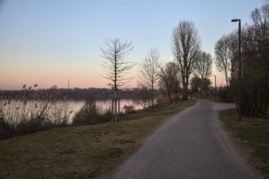 Alacakaranlıkta parktaki gölün kıyısında bir patika.