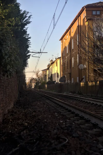 日落时在住宅区建筑物之间通过的铁路轨道 — 图库照片