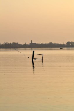Gün batımında göl ve karşı kıyıda bir kasaba.
