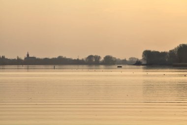 Gün batımında göl ve karşı kıyıda bir kasaba.