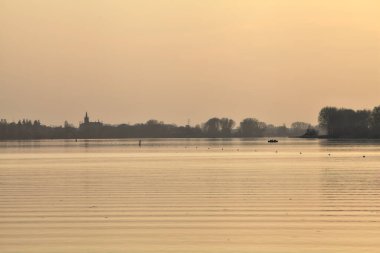 Gün batımında göl ve karşı kıyıda bir kasaba.