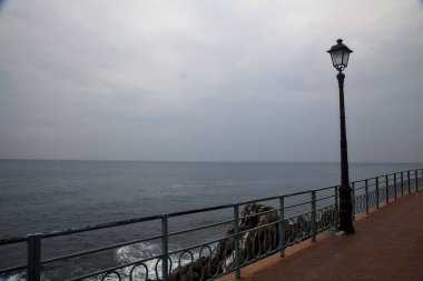 Bulutlu bir günde deniz kenarında sokak lambası olan panoramik patika