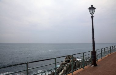 Bulutlu bir günde deniz kenarında sokak lambası olan panoramik patika