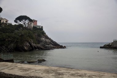 Bulutlu bir günde tepesinde bir ev olan uçurumlar tarafından kapatılmış körfez.