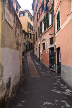 Bulutlu bir günde yüksek binalarla çevrili dar bir dağ yolu.