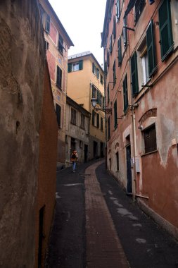 Bulutlu bir günde yüksek binalarla çevrili dar bir dağ yolu.
