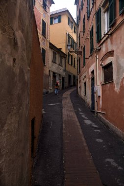 Bulutlu bir günde yüksek binalarla çevrili dar bir dağ yolu.