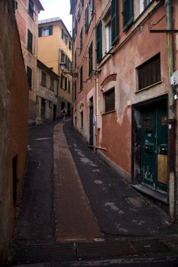 Bulutlu bir günde yüksek binalarla çevrili dar bir dağ yolu.